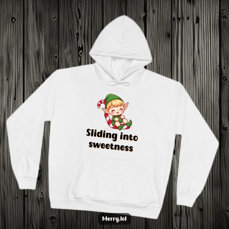 Funny hoodie showing a cute elf character hilariously sliding down a colorful candy cane, radiating festive joy.